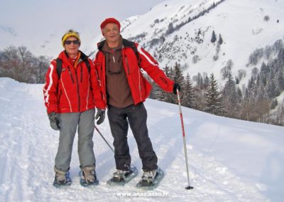 Un couple retraité en train de randonner en raquettes lors d'un séjour famille à la montagne