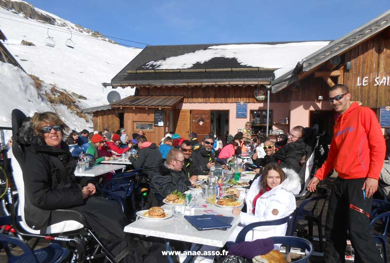 Un groupe de vacanciers en situation de handicap et leurs accompagnateurs lors d'un repas en extérieur à la montagne