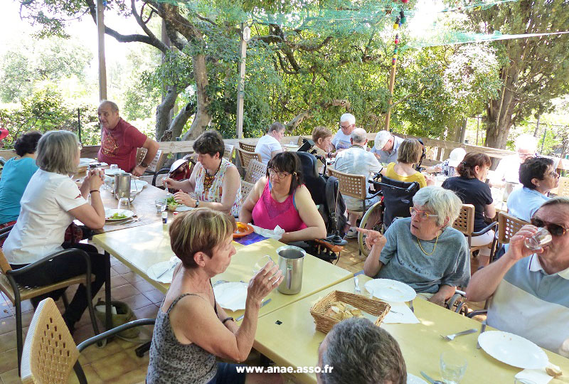 Centre de vacances Anaé à Hyères dans le Var. Un groupe de vacanciers en situation de handicap mange sur une terrasse ombragée.