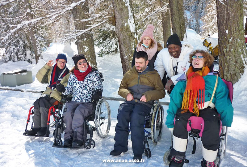 Un groupe de vacanciers en fauteuil roulant sur la neige, lors d'un séjour adapté handicap avec l'association Anaé Vacances