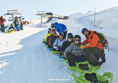 Des vacanciers font de la luge avec leur accompagnateur lors d'un séjour adapté aux personnes déficientes intellectuelles