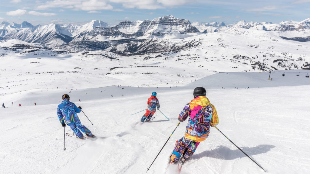 Une famille fait du ski avec un beau décor de montagnes enneigées.