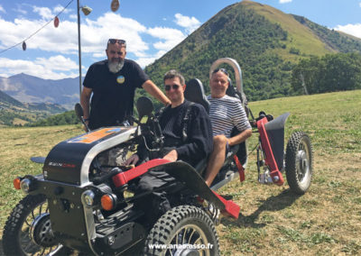 Activité adaptée PMR à la montagne. Un vacancier avec handicap moteur pilote un swincar.