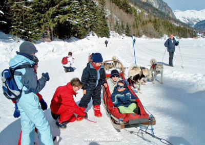 Un groupe d'enfants fait une balade en chiens de traîneaux lors d'une classe de neige avec Anaé Vacances en Savoie.