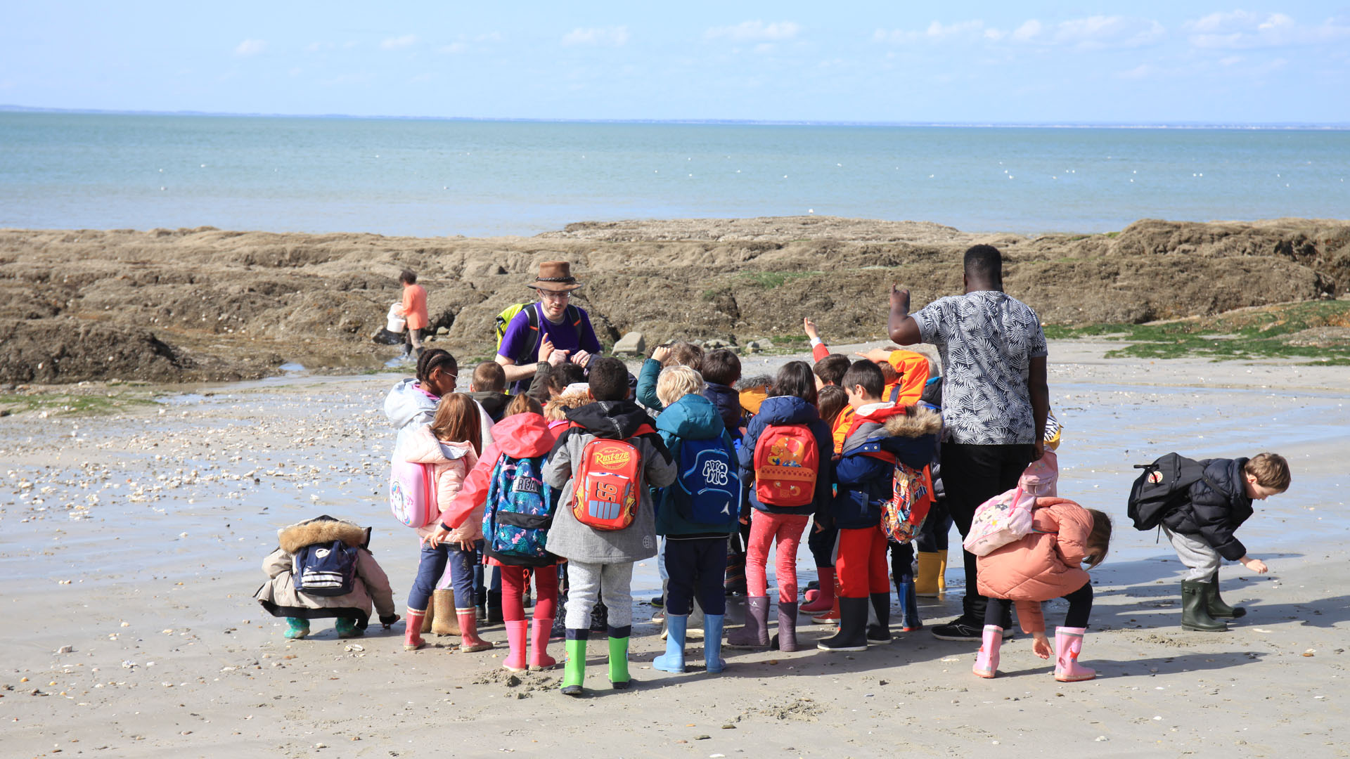 Classe de mer à Piriac en Loire-Atlantique avec Anaé Vacances. Un groupe d'élèves écoute leur professeur sur une plage.