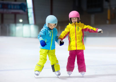 Des enfants font du patin à glace à la patinoire de Pralognan la Vanoise. Classe de neige en Savoie avec Anaé Vacances.